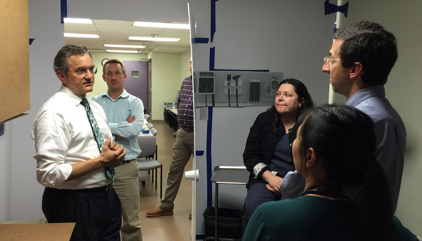 Page Principal Kurt Neubek leads participants from Healthcare for the Homeless-Houston through a mock exam room to assess spatial needs and layout. - Page