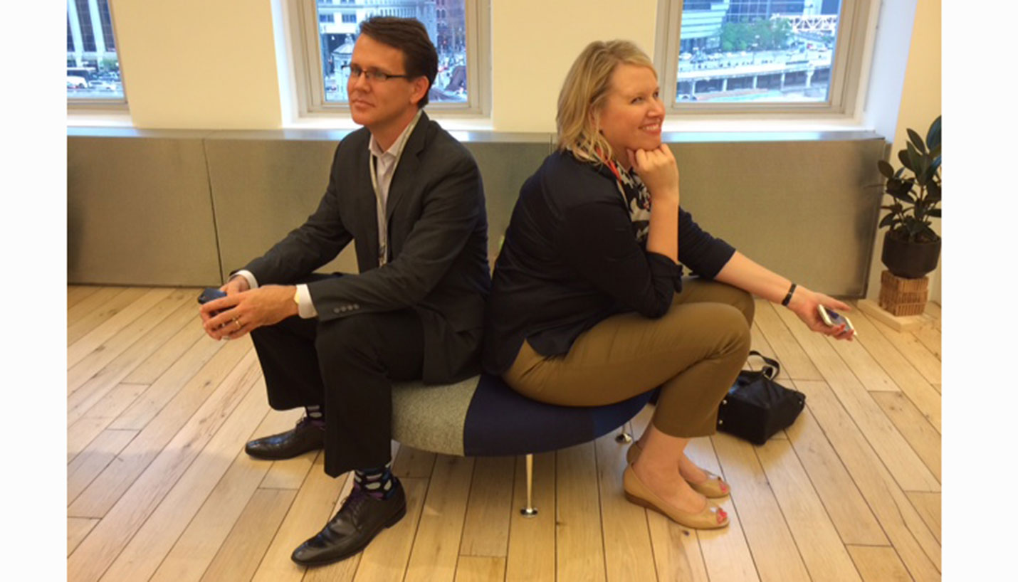 Page Interiors team members David Euscher and Stephanie Gibson test the comfort level of a Herman Miller ottoman. - 