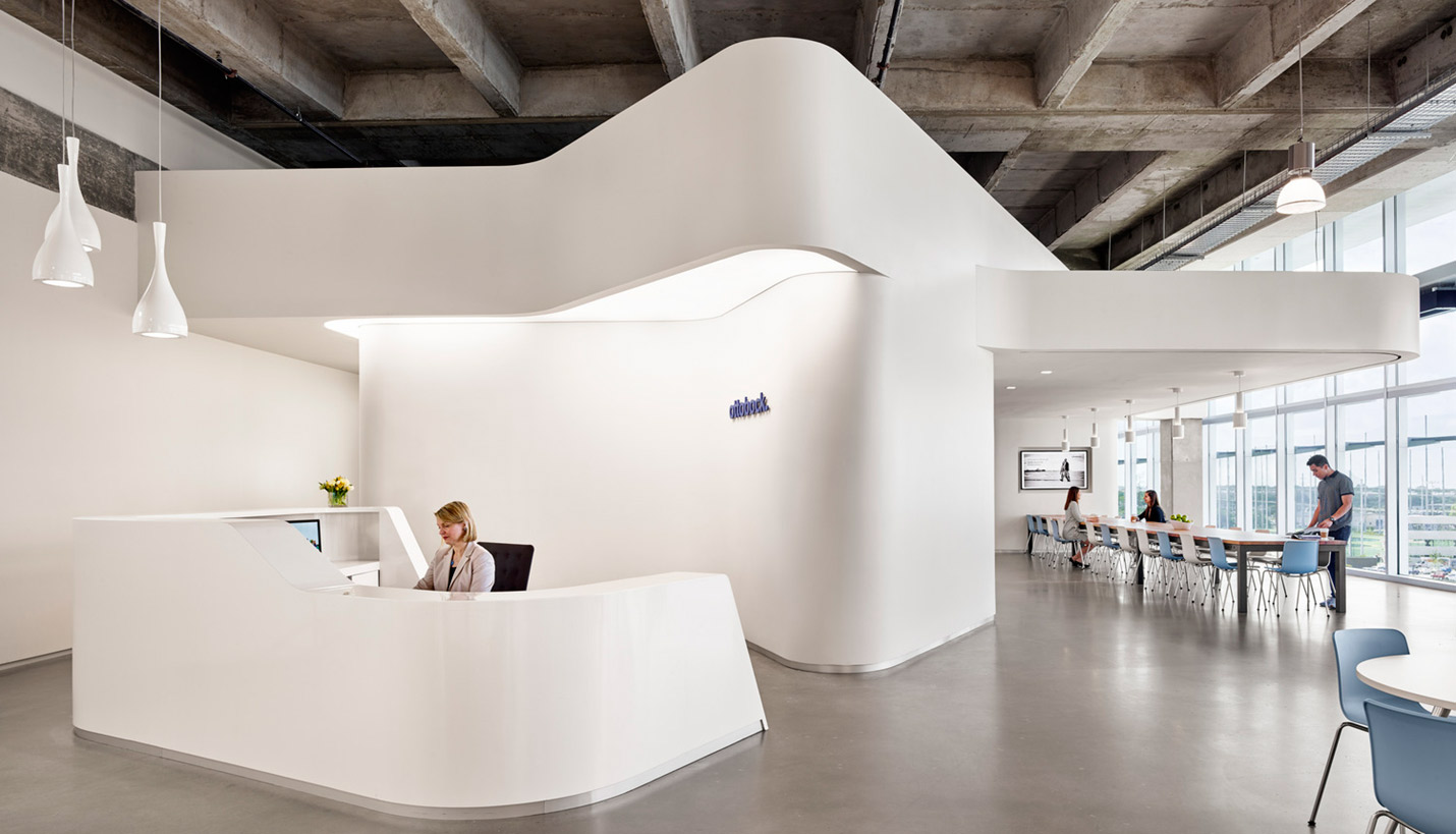 White sculptural forms cantilever over the reception and employee lounge areas. The expansive white walls are an homage to the company's Bauhaus-era offices in eastern Germany. - © Casey Dunn Photography