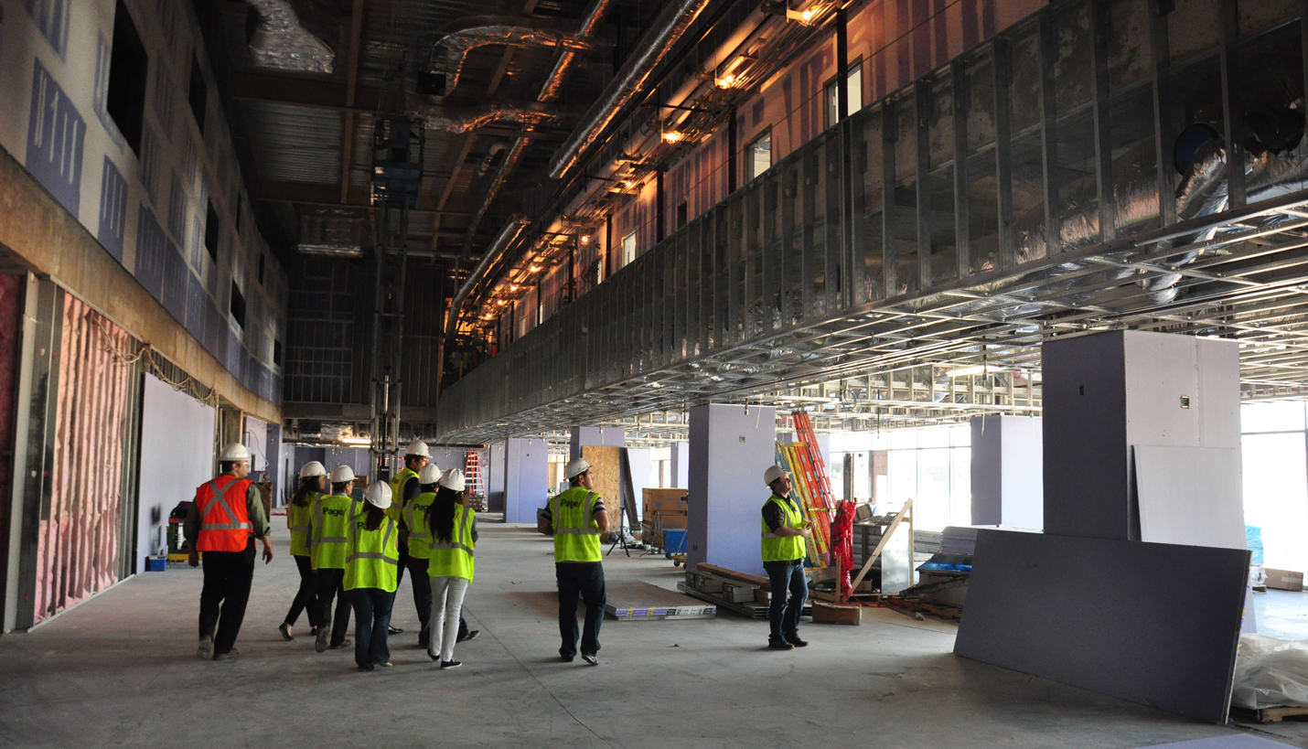 Beneath The Walls: Students stand in the Club Level, which was designed with double height volume. The interior Suite Level walkway is above. (07/25/2014) - Page